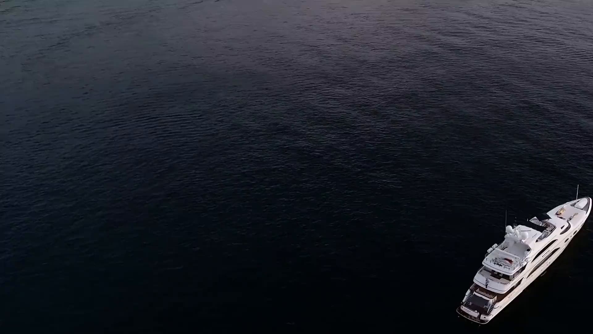 A superyacht on open water at dusk, seen from above